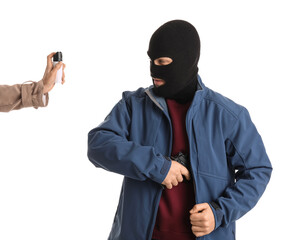 Armed thief and woman with pepper spray for self-defence on white background