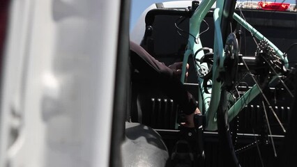 Athletic male cyclist taking road bike out of truck