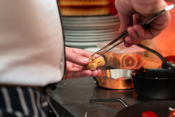 Obraz na płótnie Canvas Using chef tweezers to plate garlic on a black plate