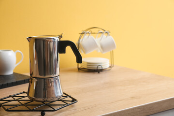 Grid with geyser coffee maker on kitchen counter near yellow wall