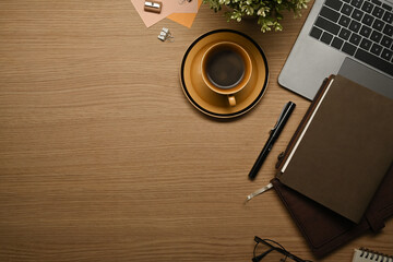 Top view of wooden working with laptop, books, glasses and coffee cup. Copy space for your text - obrazy, fototapety, plakaty
