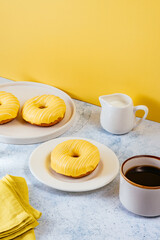 lemon doughnut in yellow glaze, coffee in a glass. 