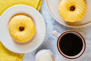 lemon doughnut in yellow glaze, coffee in a glass. 