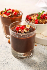 Glasses and bowl of delicious chocolate pudding, cranberry and almond on white table