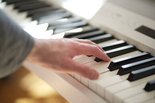 A man's hand expertly playing a white grand piano. The focus and attention to detail in this image capture the essence of musical talent and passion. Ideal for use in music-related projects.