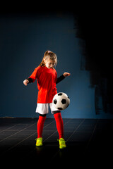 The girl football player is having fun with the ball indoors