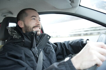 A happy young man driving a car with a big smile on his face, enjoying the trip 