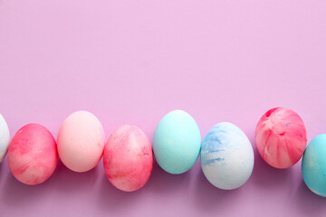 Row of painted Easter eggs on lilac background