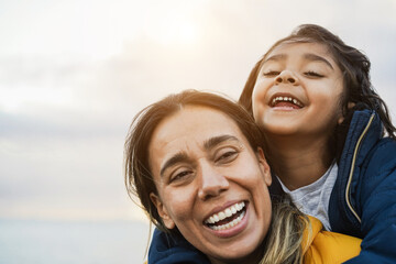 Happy latin mother and daughter having fun during winter time - Mom day concept - Main focus on...