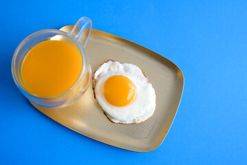 Fried eggs, scrambled eggs with orange juice on a blue background. Breakfast Top view. Minimalist food fashion concept.