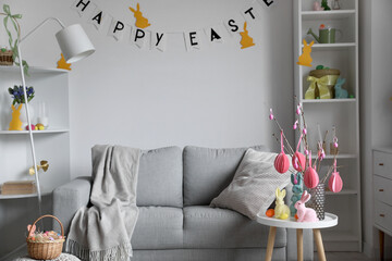 Interior of living room with Easter eggs, tree branches and rabbits