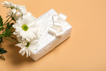 Obraz na płótnie Canvas Beautiful chrysanthemum flowers and gift for Women's Day celebration on beige background