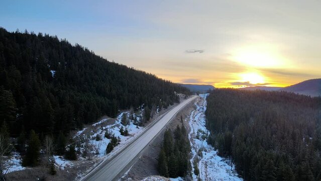 An Aerial shot of Cars driving on Cariboo Highway 97 During a Winter Sunrise in British Columbia, Canada