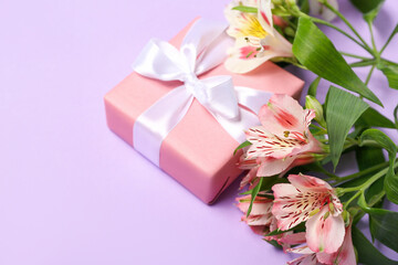 Fototapeta na wymiar Beautiful alstroemeria flowers and gift for Women's Day celebration on lilac background