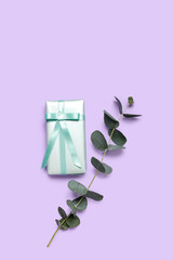 Eucalyptus leaves and gift for Women's Day celebration on lilac background
