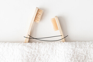 Two eco-friendly bamboo toothbrushes in love hugging on white background. The concept of cosmetic...