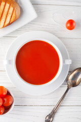 Tomato soup in a white bowl on a wooden background. View from above. copy space