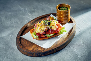 Toast with bacon, sausages and melted cheddar cheese. Concrete background, morning light