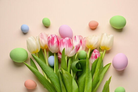 Composition with beautiful tulip flowers and painted Easter eggs on color background