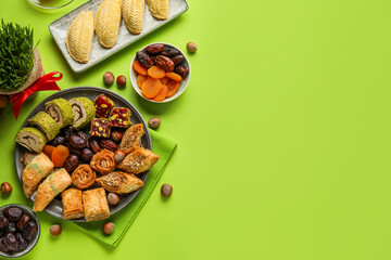 Plates with treats and grass on green background. Novruz Bayram celebration