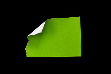 Green torn paper piece isolated on black background