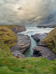 Obraz premium Stunning rough coast line of Ireland near Bridges of Ross, county Clare. Irish seascape. Beautiful nature scenery with cliffs and ocean and dramatic sky. Travel landmark.