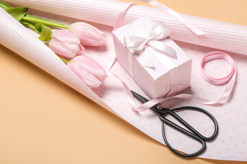 Composition with gift box, wrapping paper, scissors, ribbon and tulip flowers on color background. Women's Day celebration