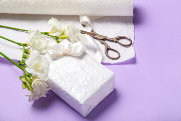 Composition with beautiful gift box, freesia flowers, scissors and wrapping paper on color background. Women's Day celebration