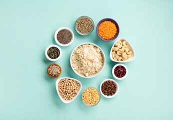 Healthy Dry Pea Protein Powder and Plant Based Protein Food (legumes, lentils, beans, seeds) on Blue Green Background.