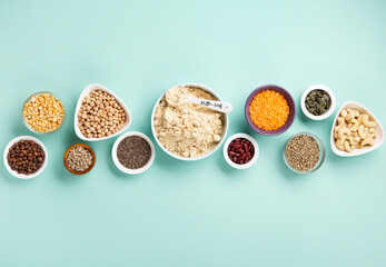 Healthy Dry Pea Protein Powder and Plant Based Protein Food (legumes, lentils, beans, seeds) on Blue Green Background.