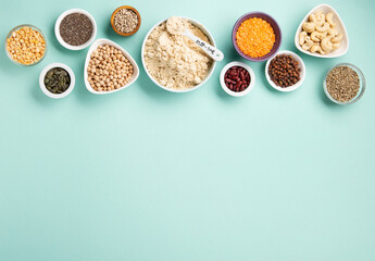 Healthy Dry Pea Protein Powder and Plant Based Protein Food (legumes, lentils, beans, seeds) on Blue Green Background.