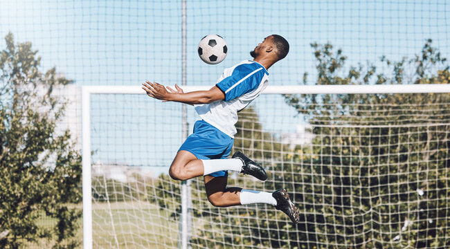 Sports, soccer and man jump with ball playing game, training and exercise on outdoor field. Fitness, workout and male football player for defence, goalkeeper and in action for goals in competition - Powered by Adobe