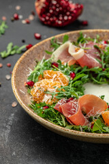 winter salad with arugula mandarins, prosciutto jamon and Parmesan cheese. place for text, top view