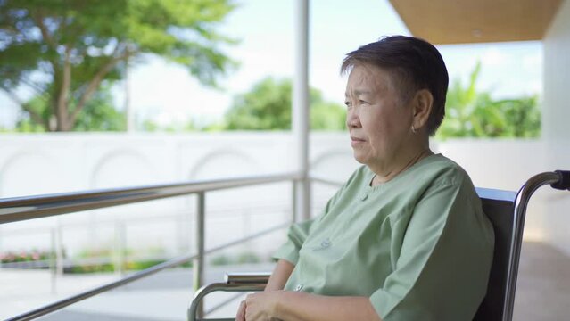 Old elderly disabled Asian patient or pensioner using wheelchair to practice to walk in nursing home in hospital. Senior people lifestyle activity recreation. Health care physical therapy