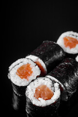 sushi roll maki with salmon on a black mirror background