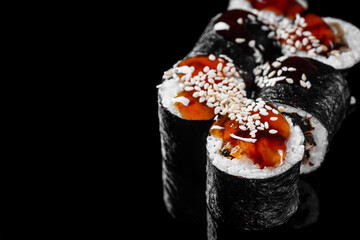 sushi roll maki with eel and unagi sauce on a black mirror background