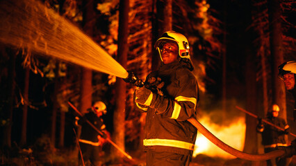 Portrait of a Handsome African American Firefighter Methodically Extinguishing a Forest Fire with...