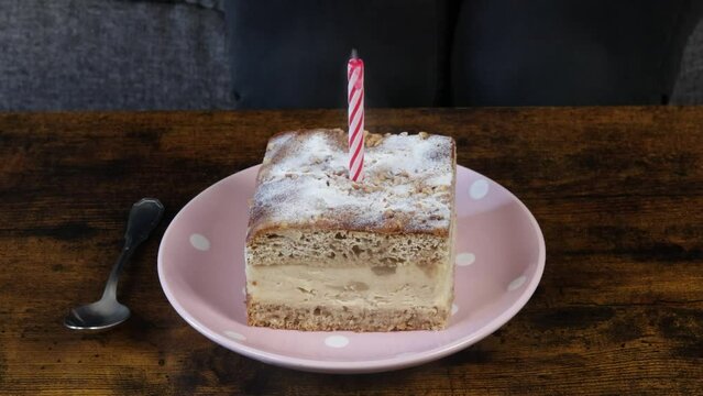 gros plan d'une personne soufflant une bougie sur une part de g&acirc;teau