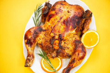 baked whole spicy chicken stuffed with oranges on a yellow background