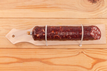 Smoked-cured sausage on special cutting board on rustic table