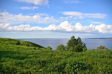 green hill with green grass and tree and Volga river with cloudscape on background in dawn