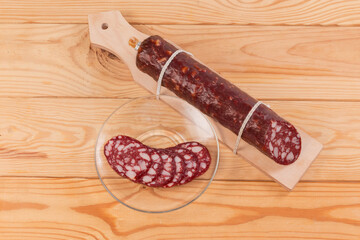 Partly sliced smoked-cured sausage on rustic table, top view