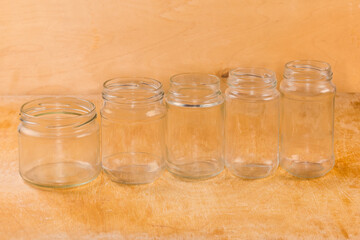 Empty small glass jars different sizes on a wooden surface