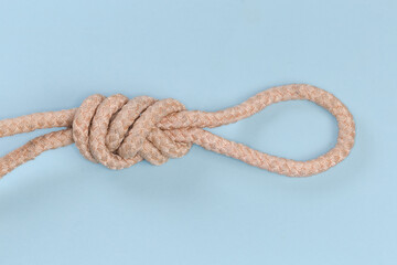 Obraz premium Rope knot Figure-nine loop on blue background close-up