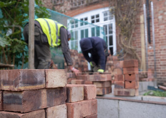 Two construction workers laying bricks as part of a renovation of an Edwardian suburban house in north London, UK