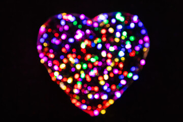 Multicolored defocused circles from the light in the shape of a heart on a black background