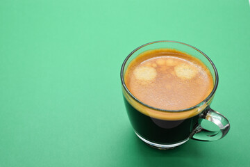 glass of hot black coffee put on green background