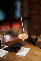 half-empty glass with a cocktail, with ice and a slice of orange are on the table in the bar. half-empty glass with ice and an orange slice.