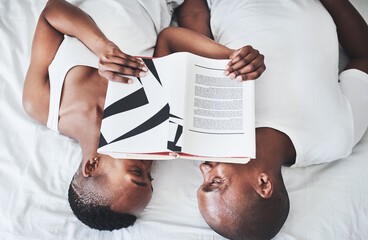 Book, reading and overhead with a black couple in bed, lying together in the morning in their home. Read, books or love with a man and woman bonding in the bedroom of their house from above