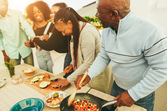 Happy african family cooking together in outdoor kitchen at home - Summer lifestyle concept - Focus on senior man head